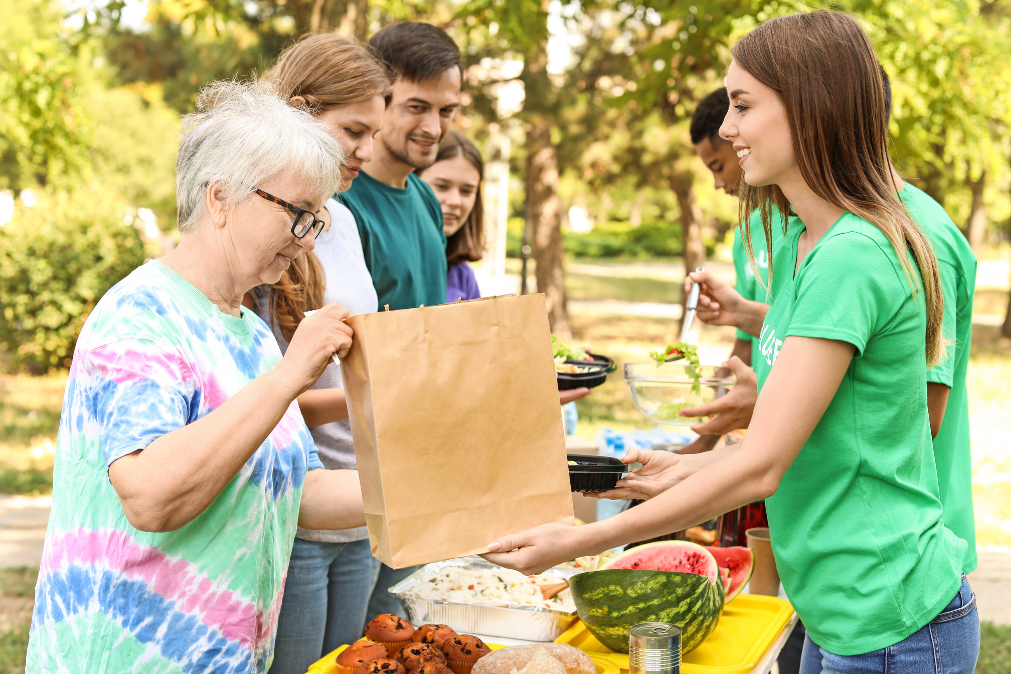 Young Volunteers Giving Food to Poor People Outdoors